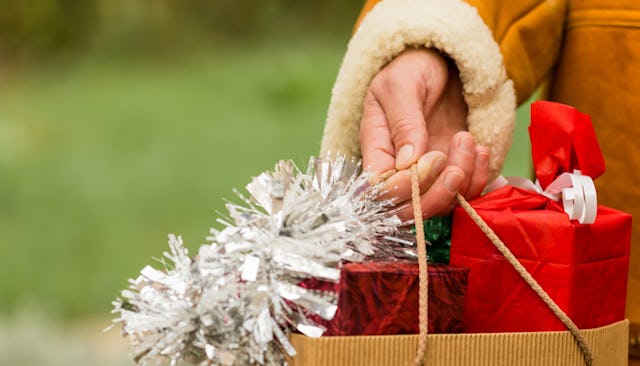 A woman's hand holding a bag full of Christmas gifts