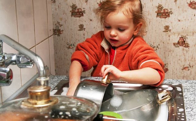A blonde girl in red shirt is doing the dishes in her home