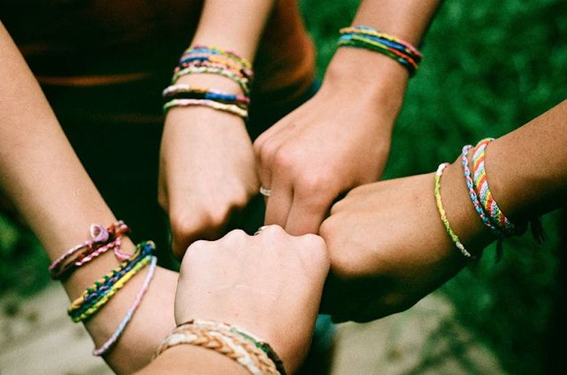 Five friends doing a circle fist bump while having best friendship bracelets on