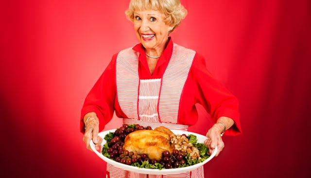 An older lady holding a Thanksgiving turkey on a plate 