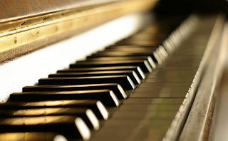 Left side of a shiny piano with black and golden keys.