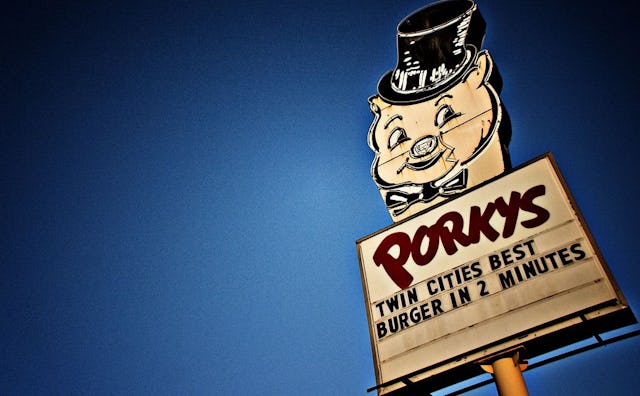 A billboard for Porkys burgers with a pig wearing a cylinder hat at the top.