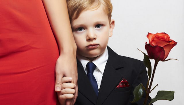 Mama's boy holding his mother's hand while wearing a black suit and holding a red rose. 