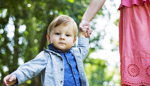 A parent walking hand in hand with their toddler.