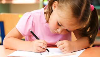 A kindergartner drawing during her class