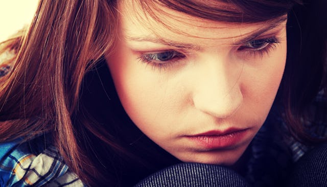 A brunette teenage girl numbly looking away.