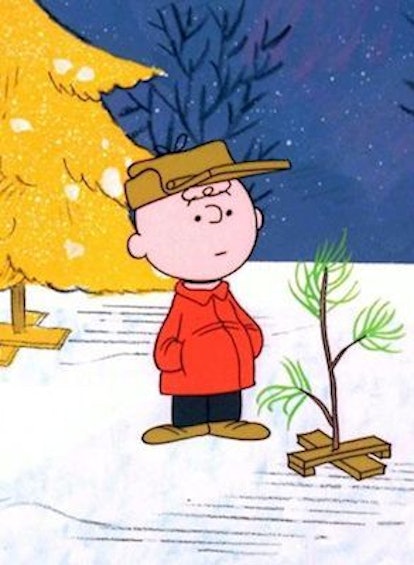Illustration of Charlie Brown standing next to a small tree plant on snow
