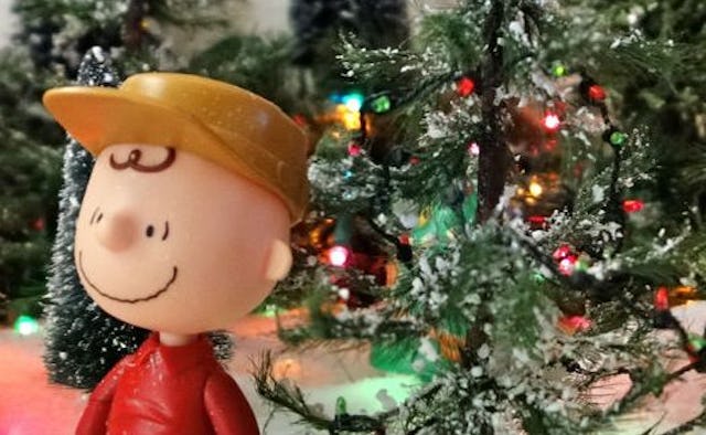 Charlie Brown doll next to a decorated Christmas tree