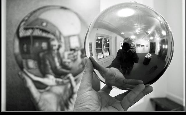 A man holding a ball with a reflective surface next to a painting of a man holding a ball with a ref...