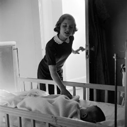 A babysitter checking up on the baby sleeping in the crib in black and white