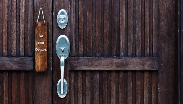 A dark brown wooden door with a metal handle and 'do not disturb' next to the handle