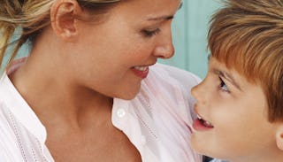 A young mother smiling and looking at her son while hugging him