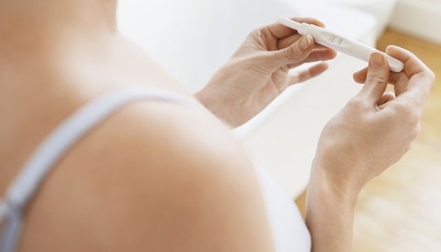 A woman holding a positive pregnancy test in her hands
