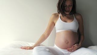 Pregnant woman sitting on a bed