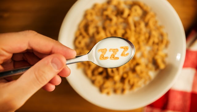 Person holding spoon with cereal over breakfast bowl