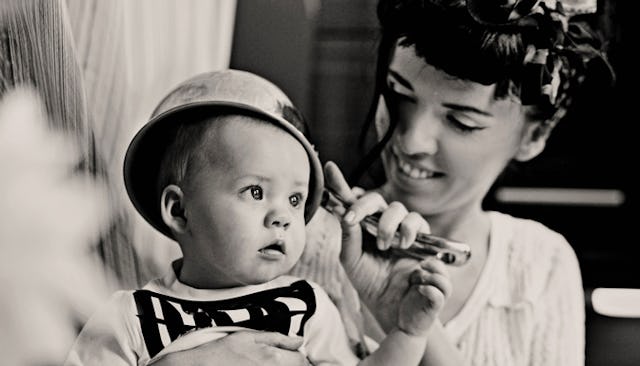 A mother holding her son in her lap while he has a pot on his had