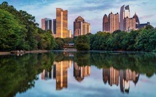 Atlanta's skyline reflected in a lake surrounded by trees