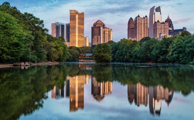 Atlanta's skyline reflected in a lake surrounded by trees