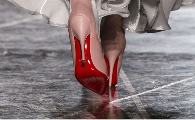 A woman walking and wearing nude Louboutin high heels