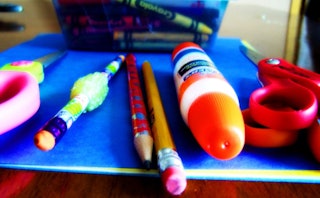 A close-up of pencils, scissors and glue laid out on a blue surface