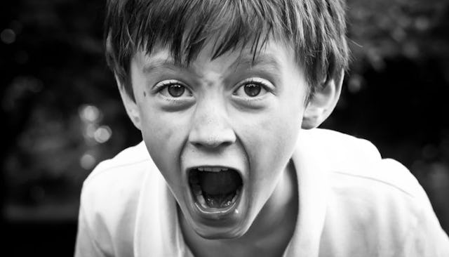 A young boy in a white shirt, screaming