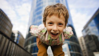 A kid leaning down, looking at the camera while smiling and plotting