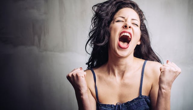 A brunette woman in a black tank top screaming happily about her husband's vasectomy