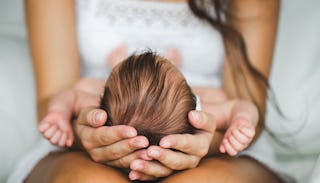 A woman holding a baby in her hands carefully