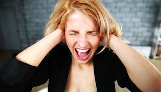A woman with misophonia holding her ears with her hands and screaming. 