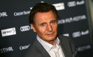 Close-up photo of Liam Neeson from Taken wearing a suit with a smirk on his face