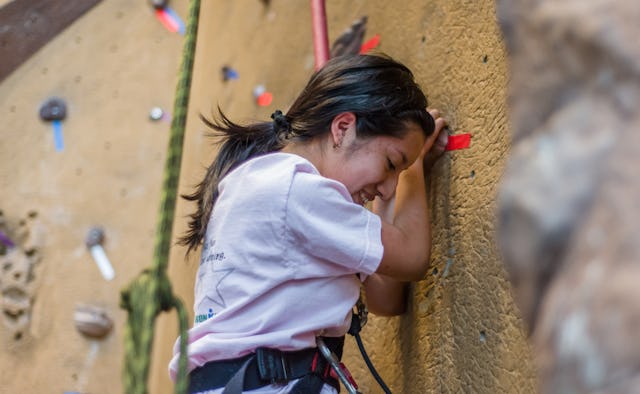 A girl climbing up an exercise climbing wall to get over self-consciousness