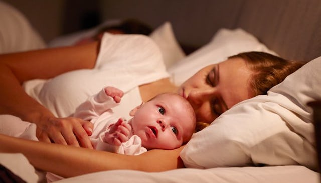 A mother co-sleeping with her baby reluctantly