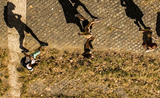 An aerial view of four kids walking down a street with their visible shadows