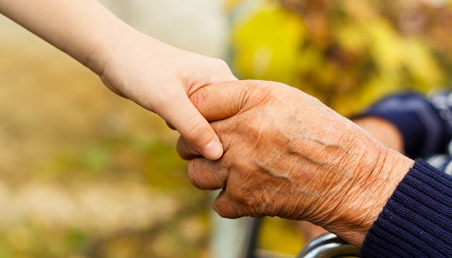 A close-up of an kid's hand holding an old man's hand