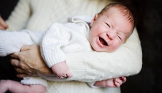 A crying newborn being held by his mother