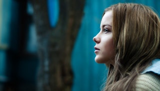 A brunette, long-haired teenage girl looking in the distance in a forest