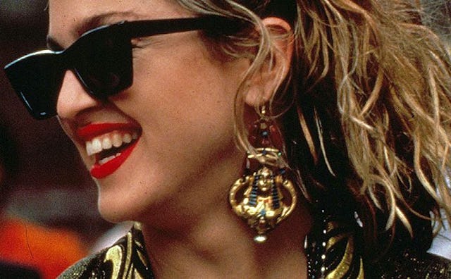 Madonna wearing red lipstick, black sunglasses, and large pharaoh-shaped earrings in 'Desperately Se...