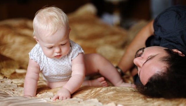 A father sleeping while his baby is awake next to him