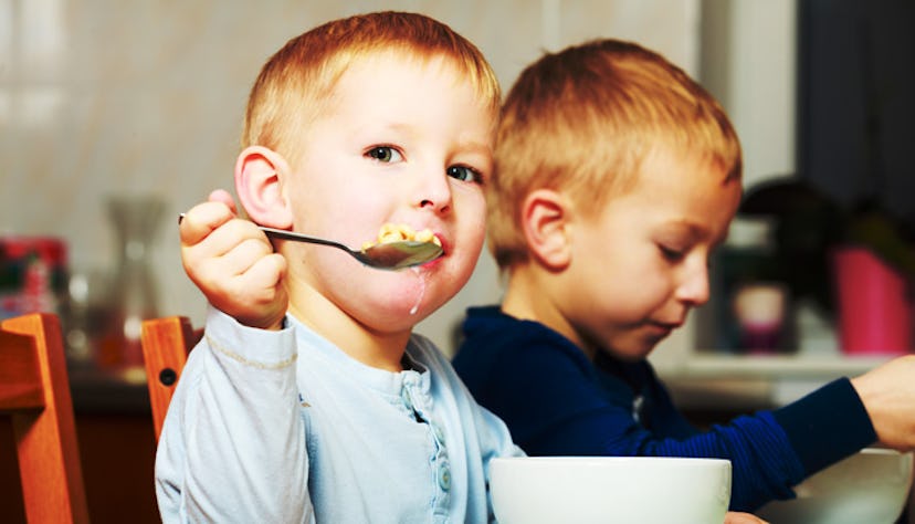 Two blond male kids sitting and eating cereal 