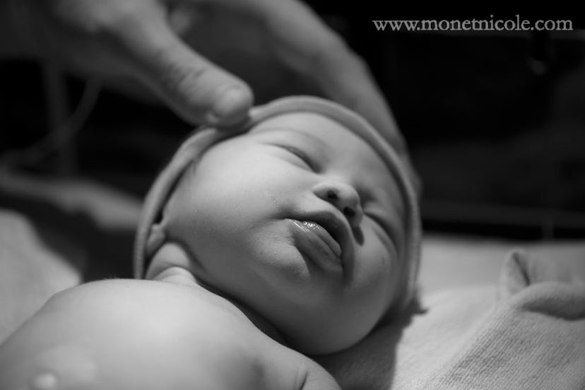 A person gently stroking a newborn baby's head while the baby is sleeping 