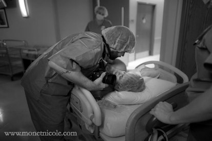 A father hugging a mother that just given birth via C-section while holding a camera in black and wh...