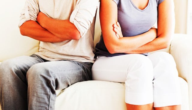 Parents sitting next to each other on a couch with their arms crossed