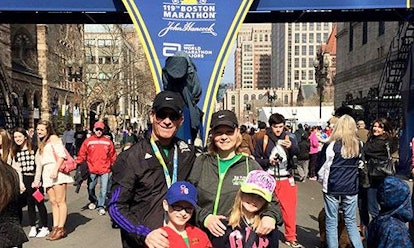 A man and a woman with their boy and girl in front of the 119th Boston Marathon sign