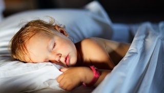 A toddler sleeping on light blue bed sheets