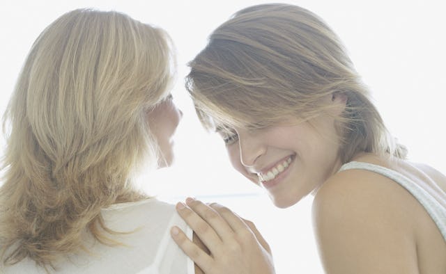 A mother and her adult daughter dressed in white, laughing and having a lovely time