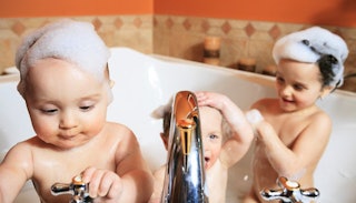 Two toddlers and one slightly older child in a bathtub taking a bubble-bath