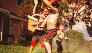 Three boys playing outside with no shirts on 
