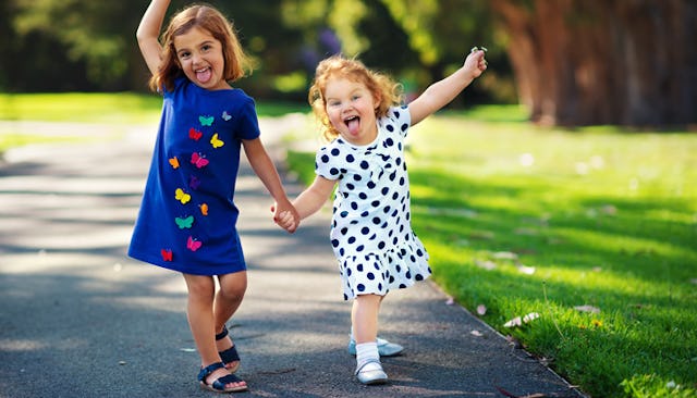 Two happy girls goofing around together having their tongues out in a park