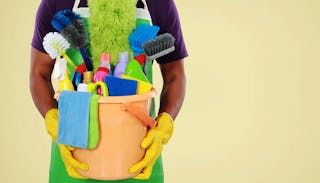 A person holding an orange bucket with cleaning products