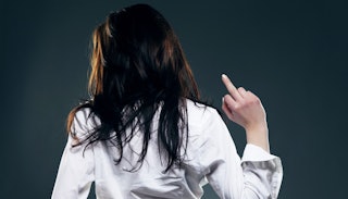 A brunette woman in a white button-up with her back turned, lifting her middle finger up 